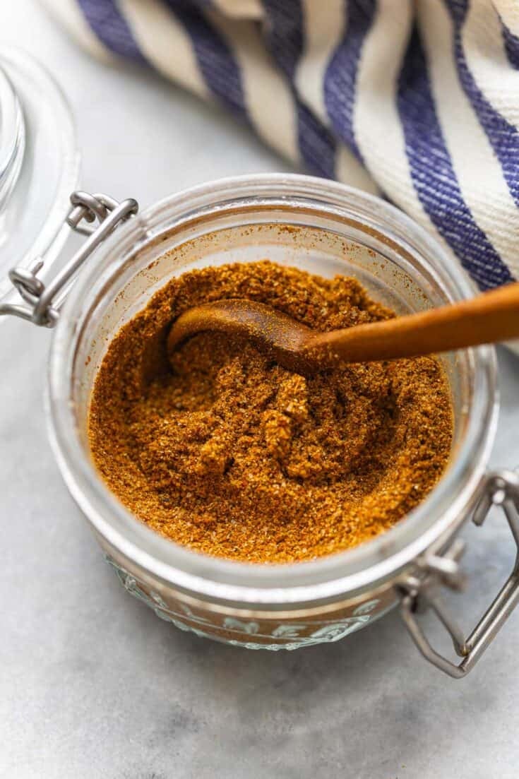 Homemade Shawarma Spice Blend in a small storage jar with a wooden spoon.
