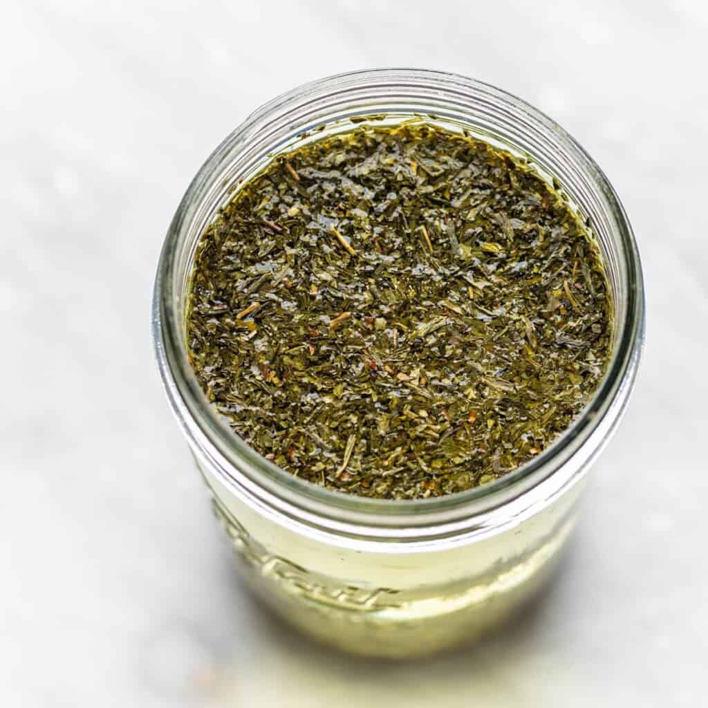 Loose leaf green tea leaves in a large quart-sized jar with water