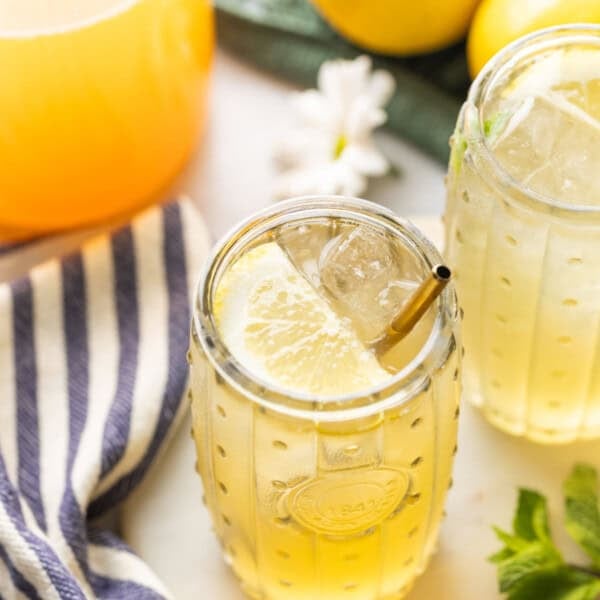 A couple of glasses of iced green tea lemonade with lemon slices inside.