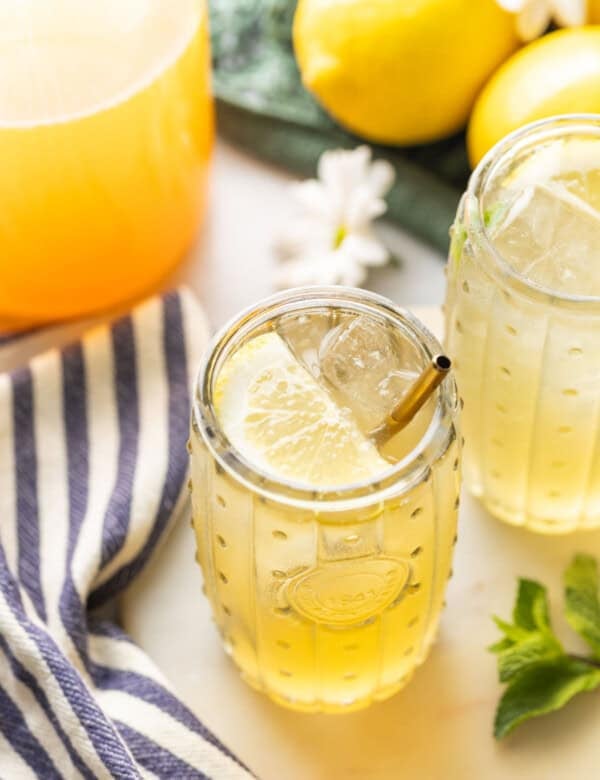 A couple of glasses of iced green tea lemonade with lemon slices inside.
