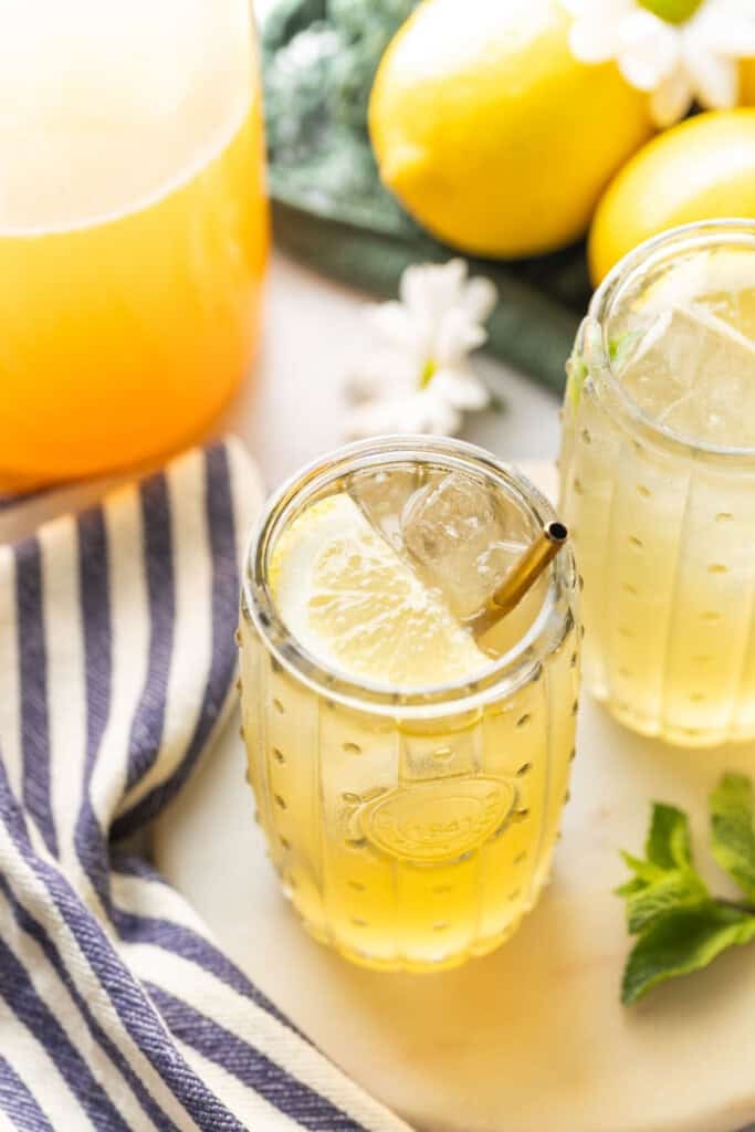 A couple of glasses of iced green tea lemonade with lemon slices inside.