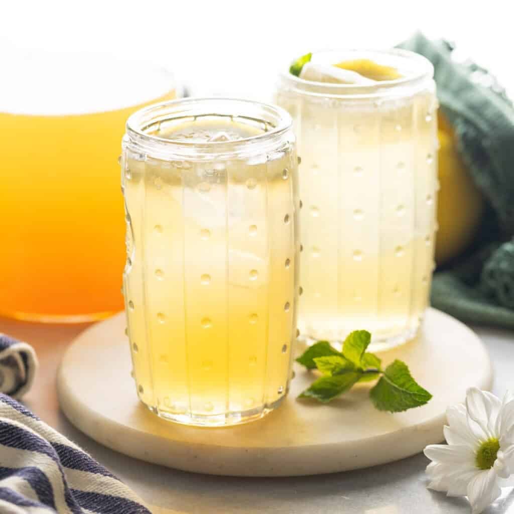 Two glasses and a pitcher full of green tea lemonade