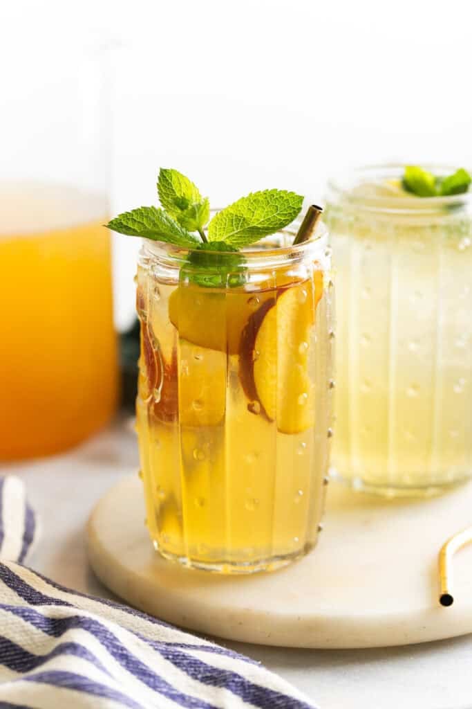An iced green tea lemonade with peach slices and fresh mint