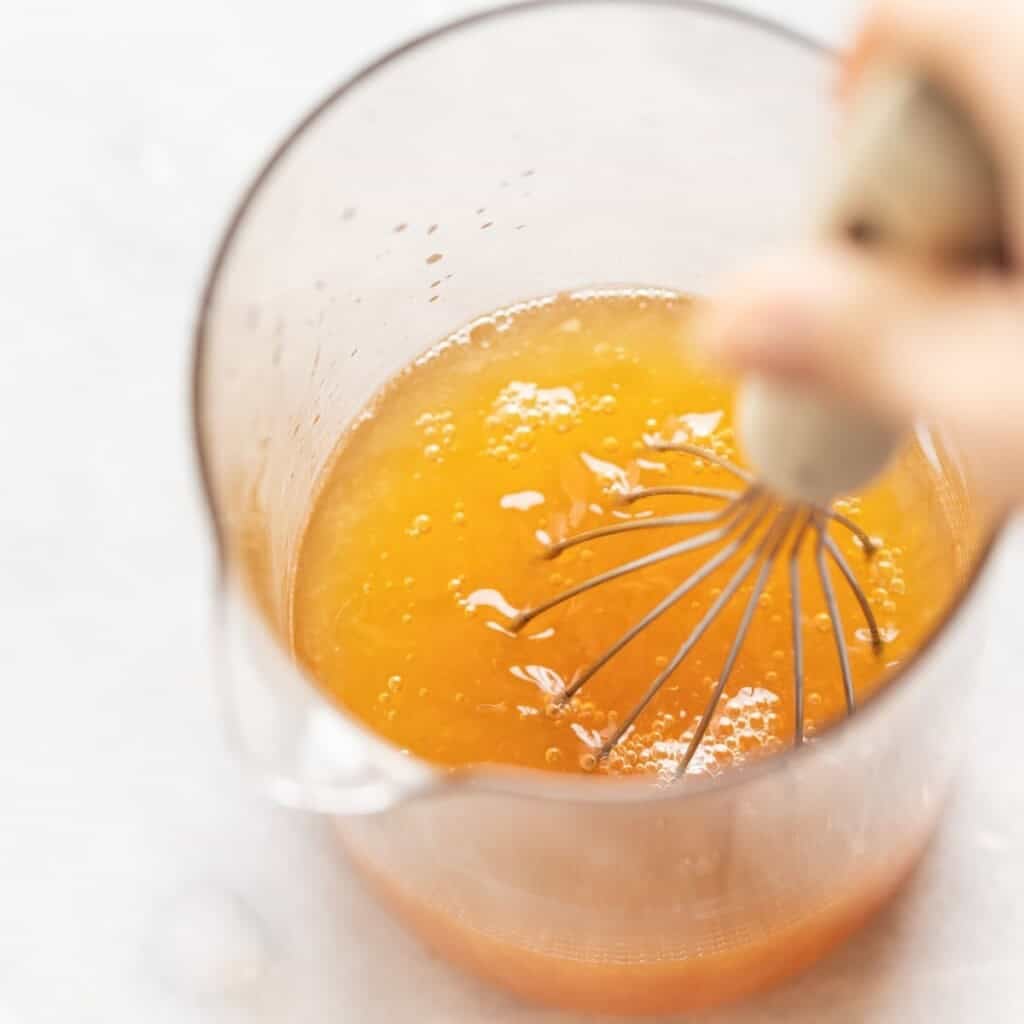 Lemon juice and honey whisking together in a large pitcher for green tea lemonade