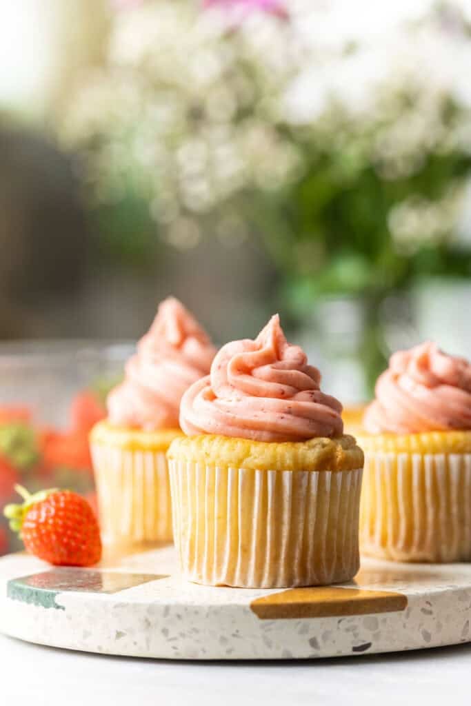 Three vanilla cupcakes frosted with strawberry buttercream