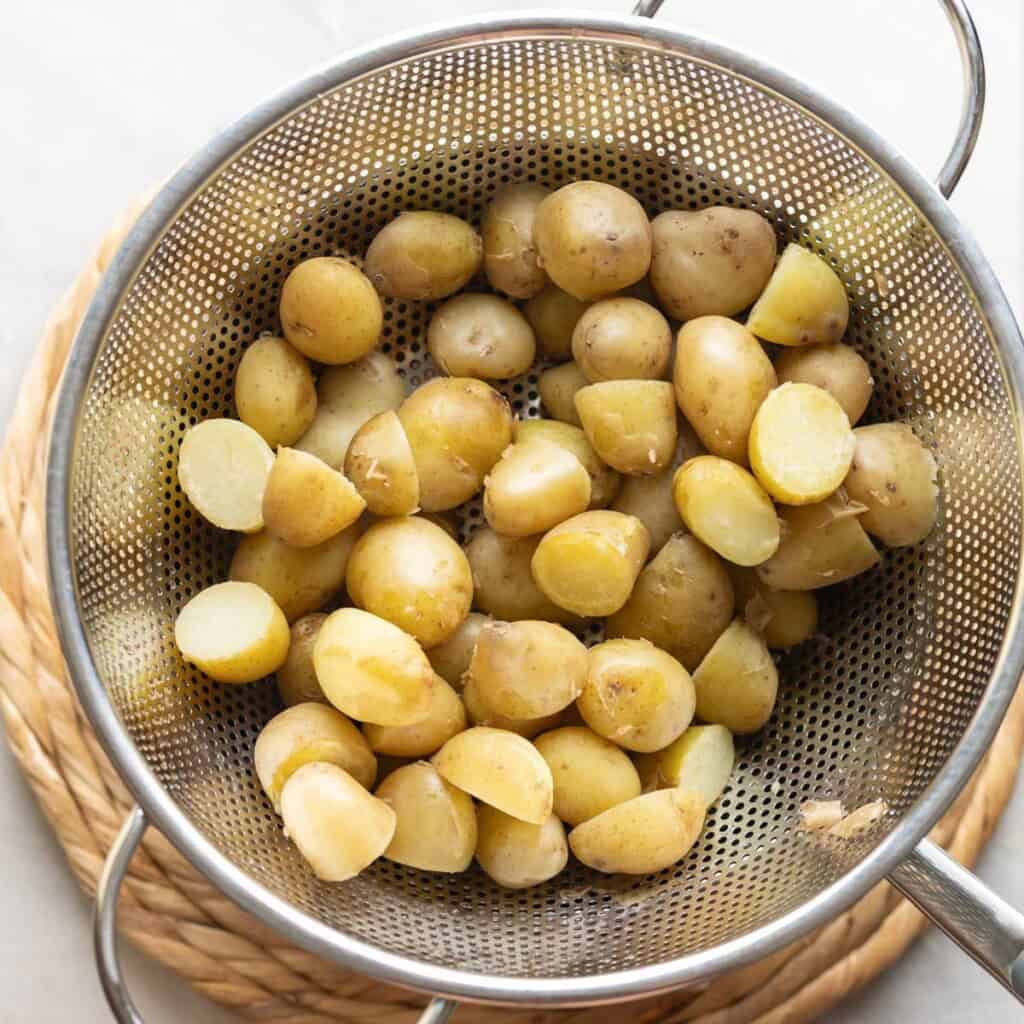 Boiled baby potatoes in a colander over a pot