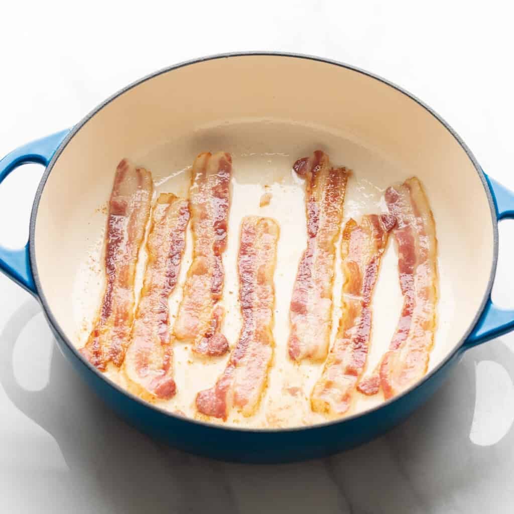 bacon slices cooking in a large casserole dish