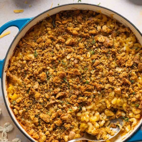 Hard cider caramelized onion & bacon mac and cheese in a casserole dish with a serving spoon inside