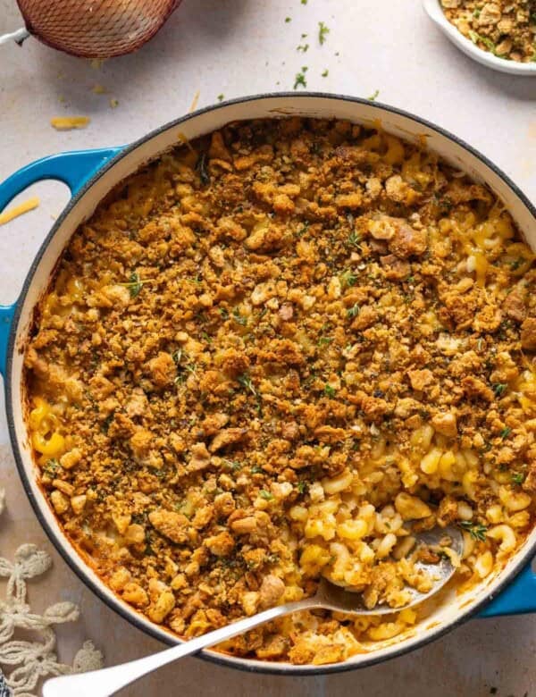 Hard cider caramelized onion & bacon mac and cheese in a casserole dish with a serving spoon inside