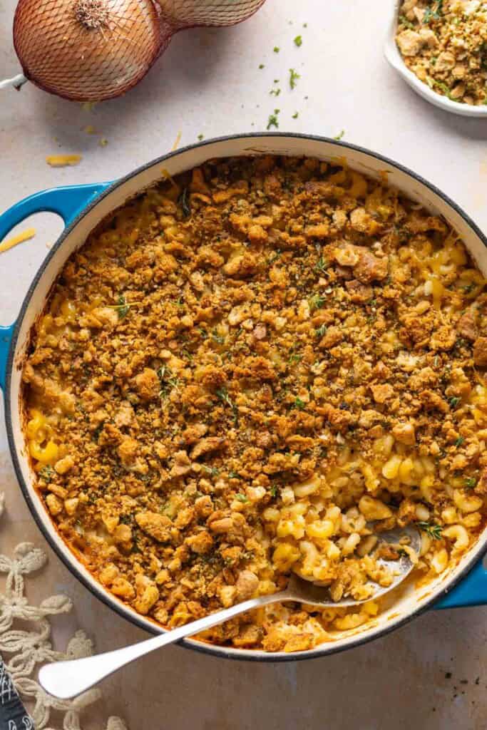Hard cider caramelized onion & bacon mac and cheese in a casserole dish with a serving spoon inside