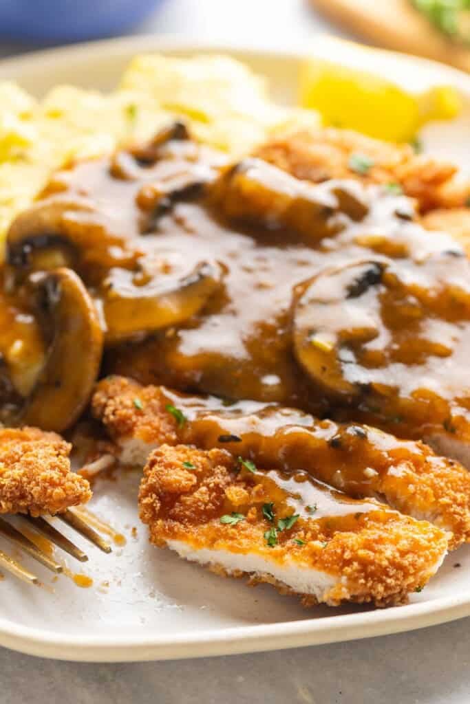 Gluten free chicken schnitzel cut into slices and topped with a mushroom gravy