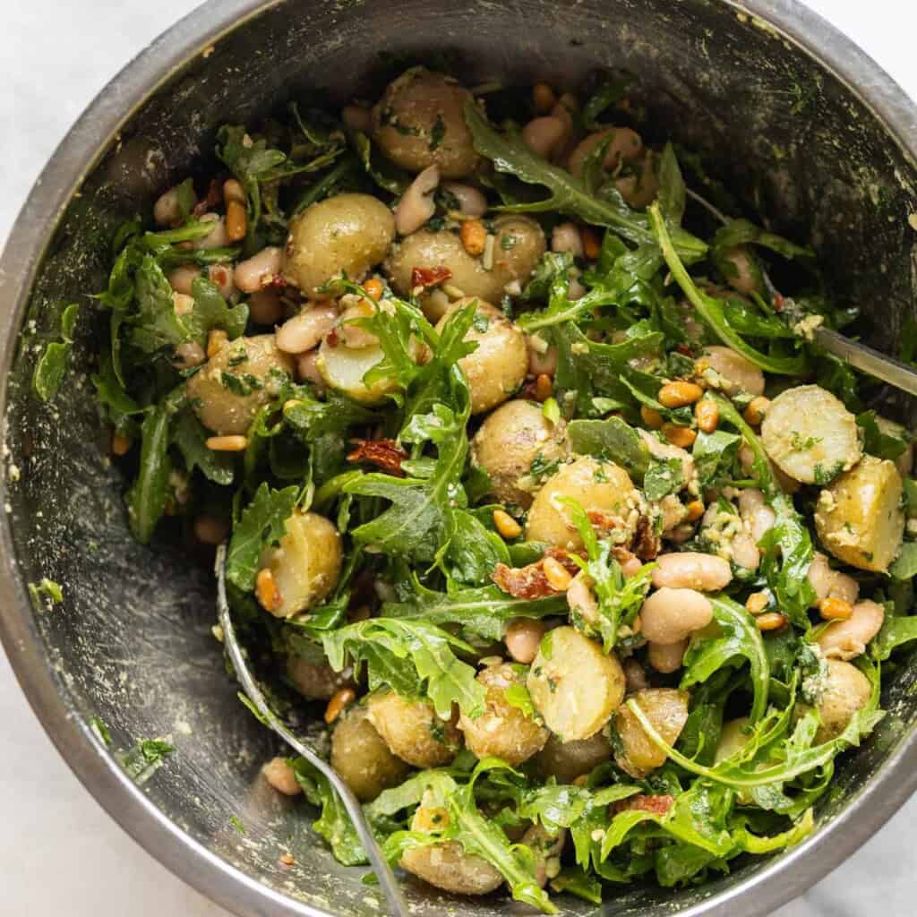 Pesto potato salad ingredients mixed together in a big bowl