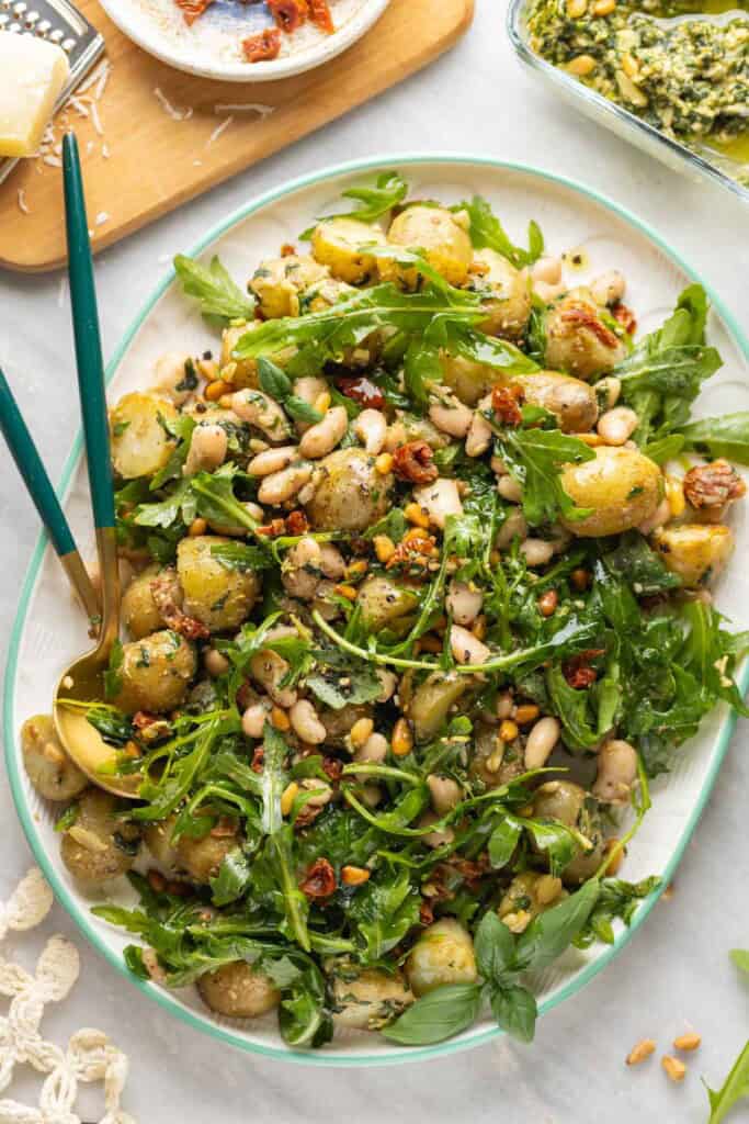 Potato Pesto Salad made with boiled potatoes, white beans, sundried tomatoes, toasted pine nuts, rocket and pesto on a serving platter: