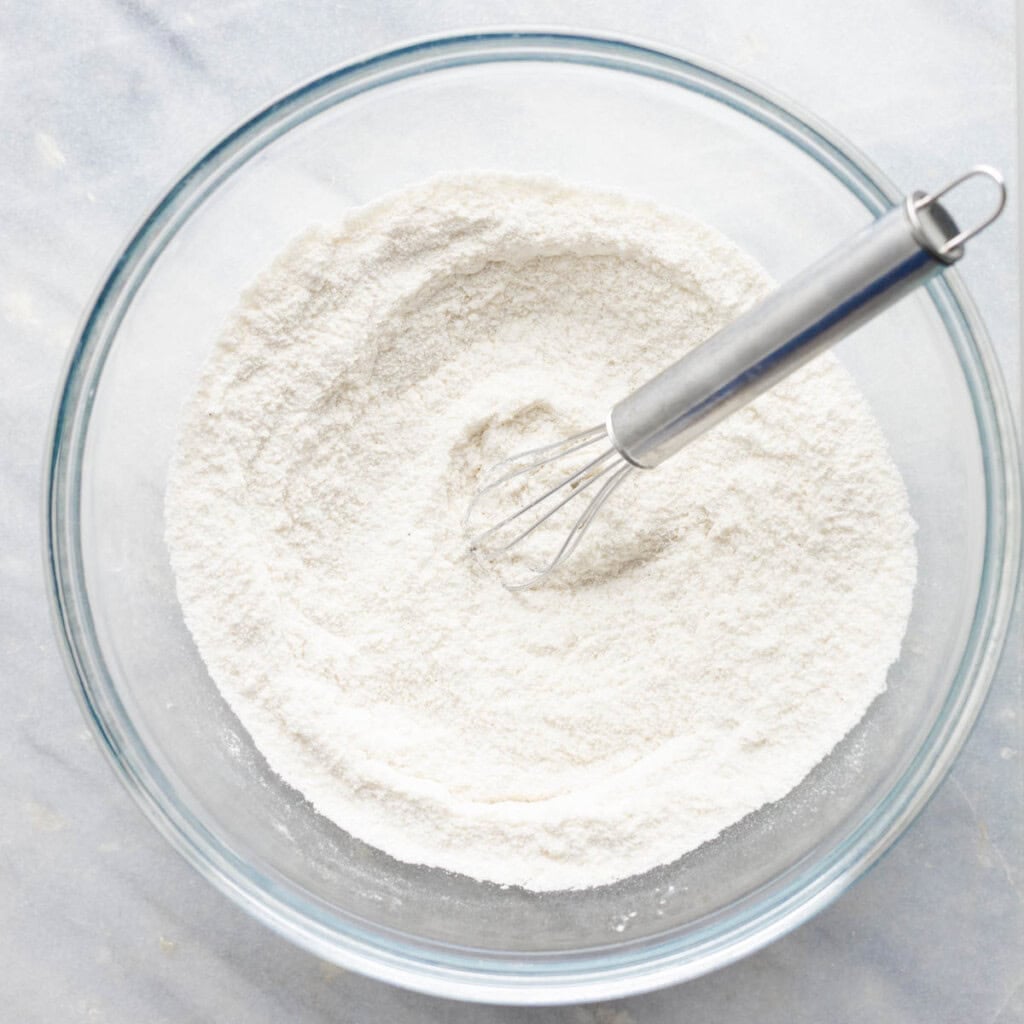 dry ingredients needed to make a gluten free cobbler biscuit topping in a mixing bowl with a whisk