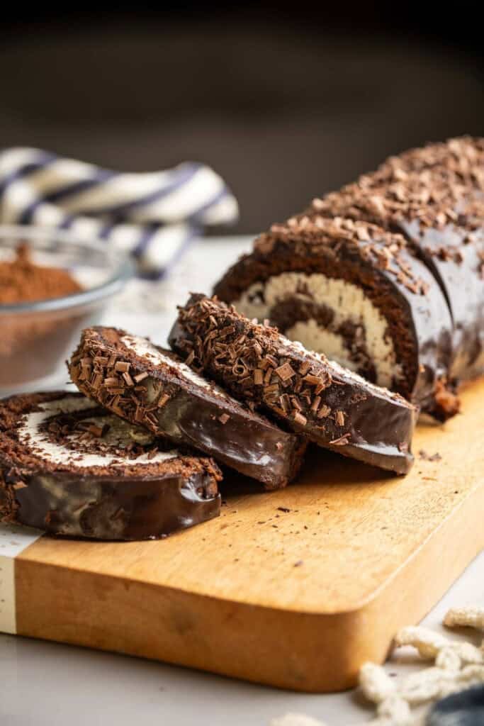 A gluten free chocolate swiss roll cake a on a cutting board with