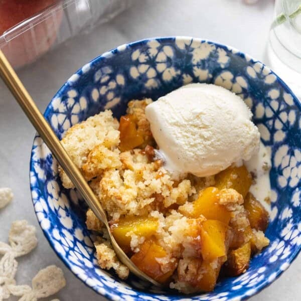 Gluten free peach cobbler in a bowl with vanilla ice cream