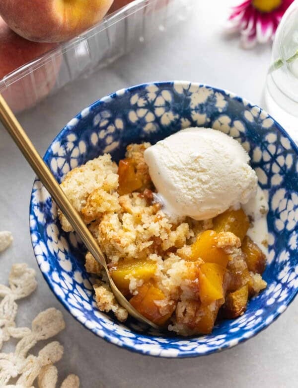 Gluten free peach cobbler in a bowl with vanilla ice cream