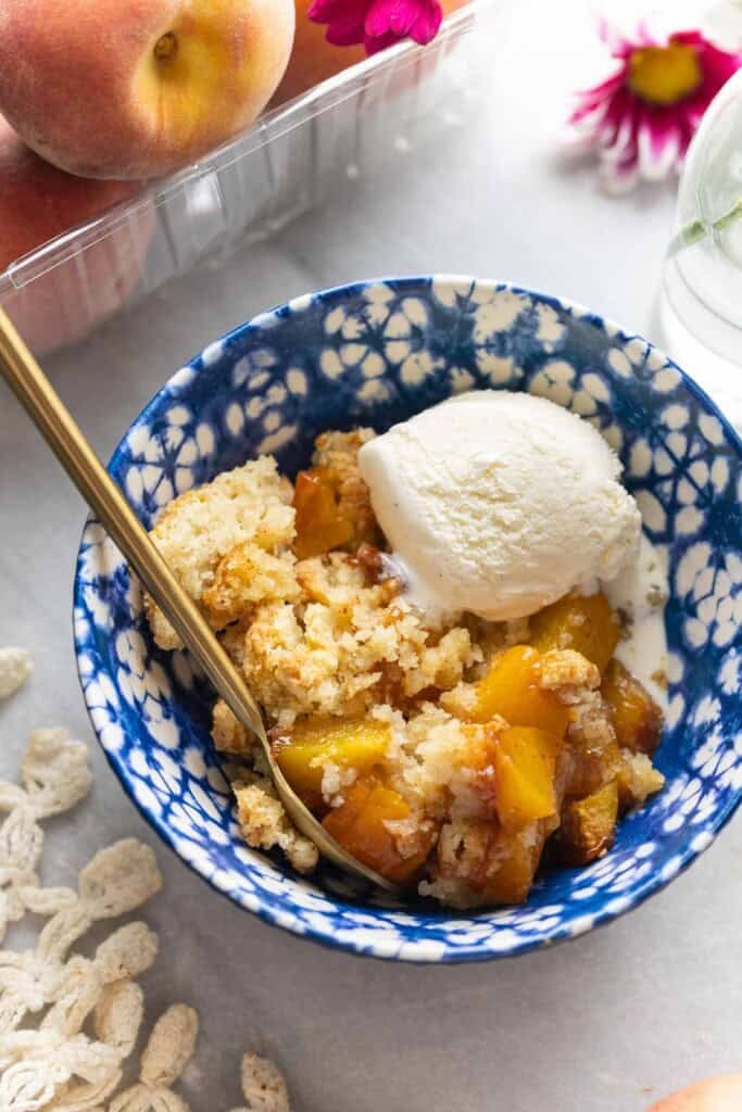 Gluten free peach cobbler in a bowl with vanilla ice cream