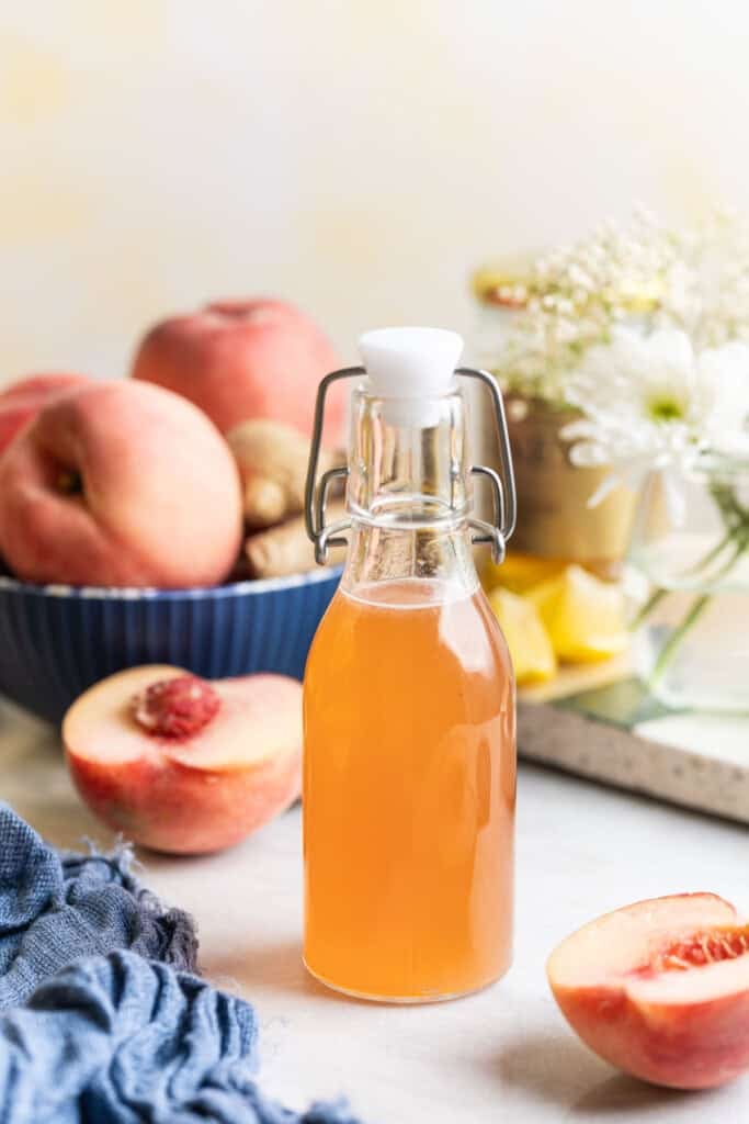 Homemade ginger & honey peach syrup in a small bottle with a swing top lid.