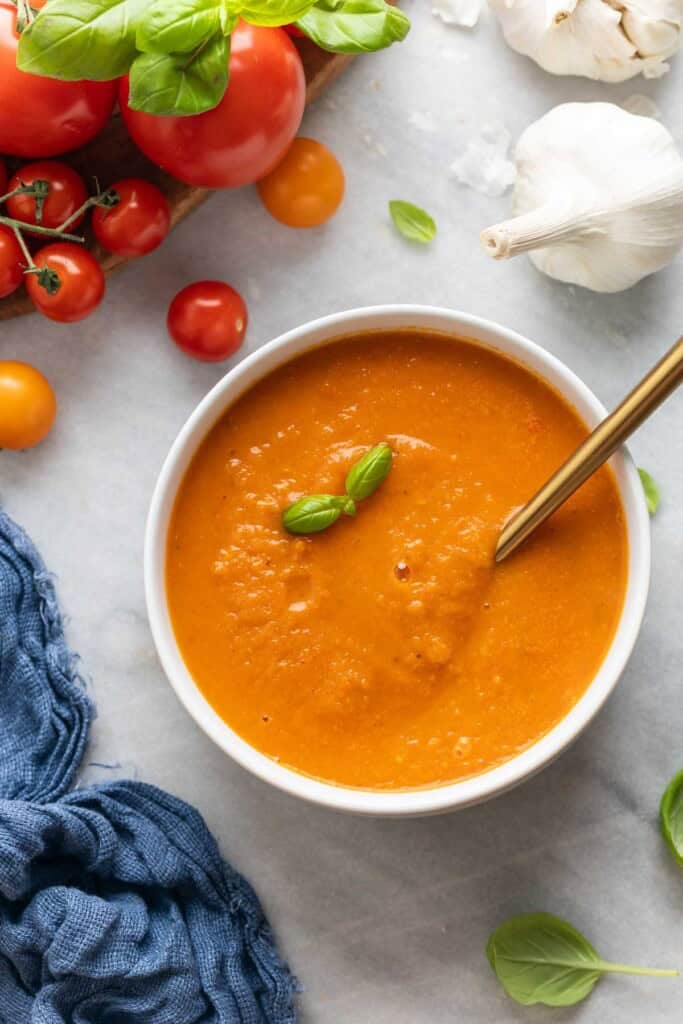 A bowl of roasted tomato soup garnished with fresh basil leaves