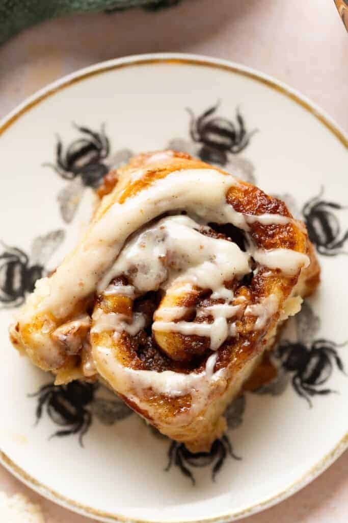 A gluten free apple cinnamon roll with a brown butter cream cheese glaze on a plate.
