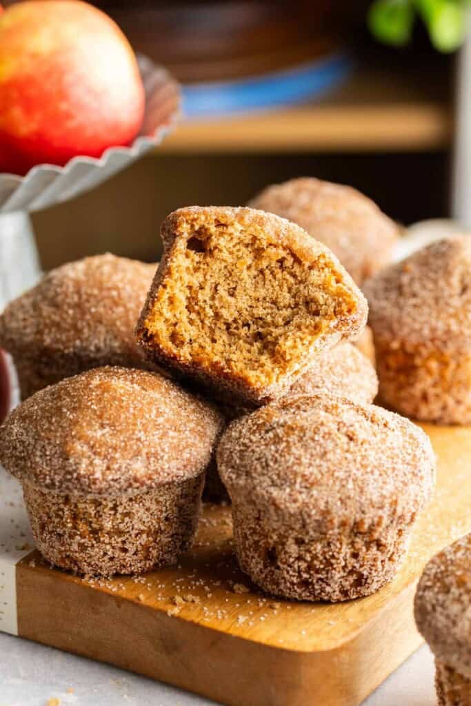 Gluten Free Apple Cider Muffins on a wooden board with a bite taken out of the muffin on top.