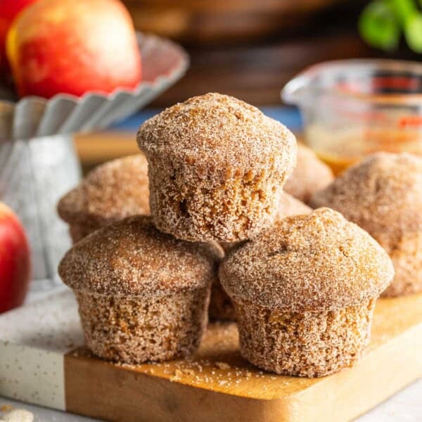 A small pyramid stack of Gluten Free Apple Cider Muffins on a wooden board.
