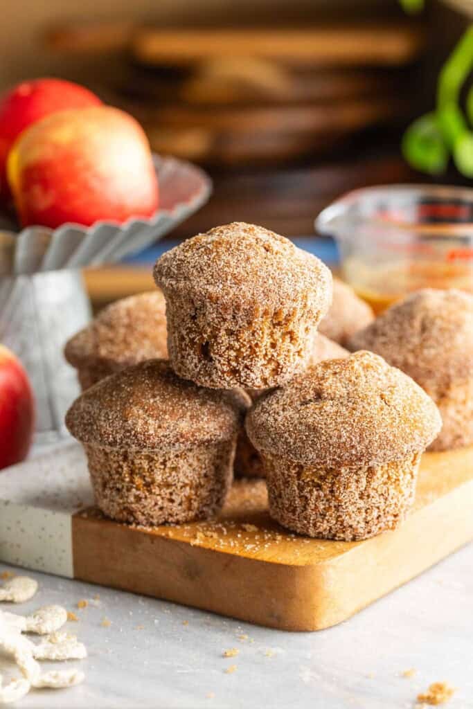 A small pyramid stack of Gluten Free Apple Cider Muffins on a wooden board.
