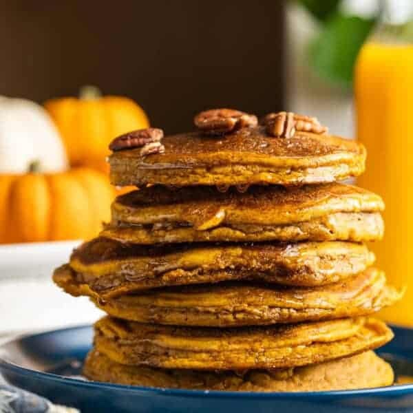A stack of gluten free cinnamon spiced pumpkin pancakes with pecans on top