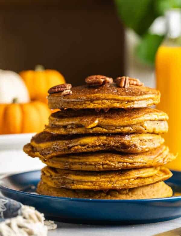 A stack of gluten free cinnamon spiced pumpkin pancakes with pecans on top