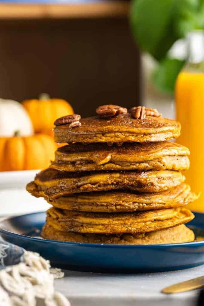 A stack of gluten free cinnamon spiced pumpkin pancakes with pecans on top